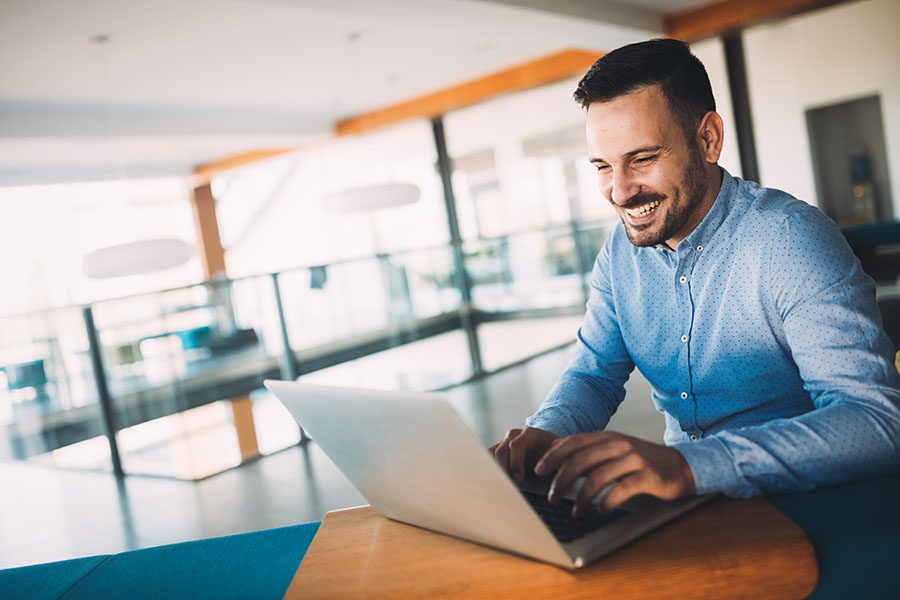Blog - Smiling Businessman Using Laptop In Modern Office